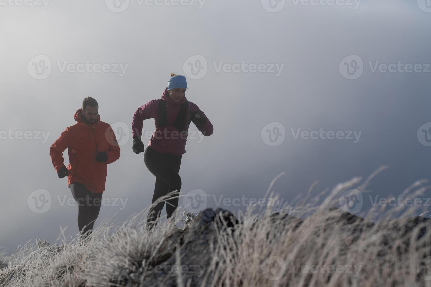 trail running couple man and woman running on a mountain path photo