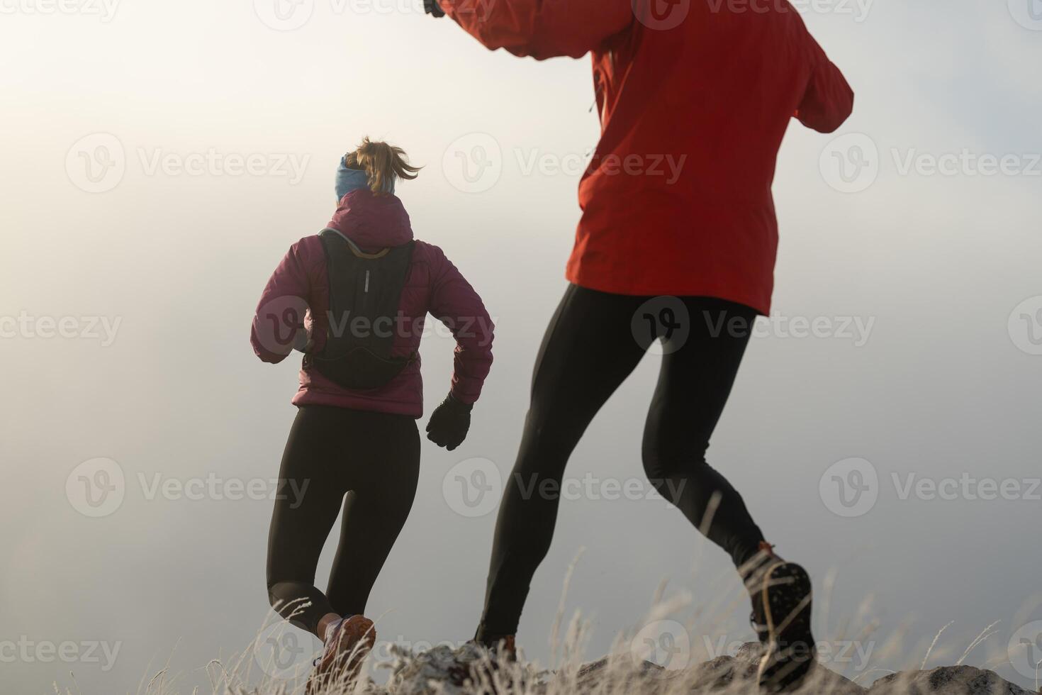 trail running couple man and woman running on a mountain path photo