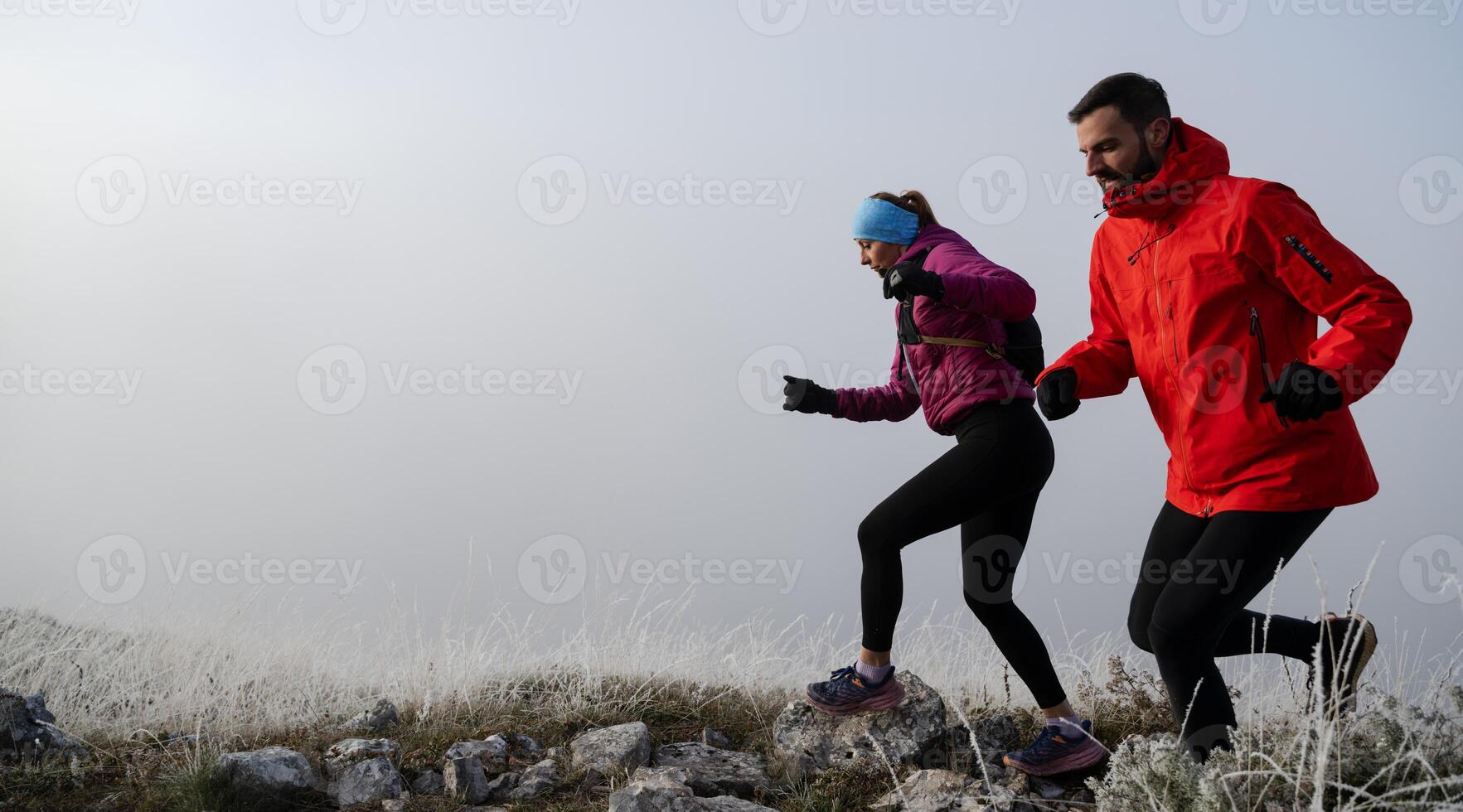 trail running couple man and woman running on a mountain path photo