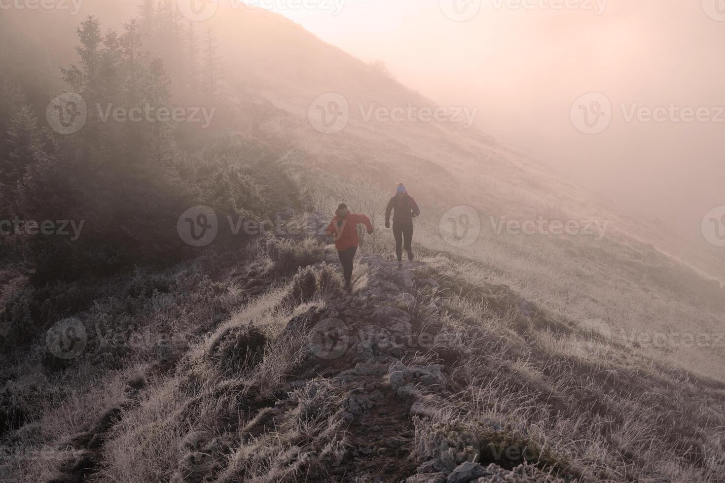 trail running couple man and woman running on a mountain path photo