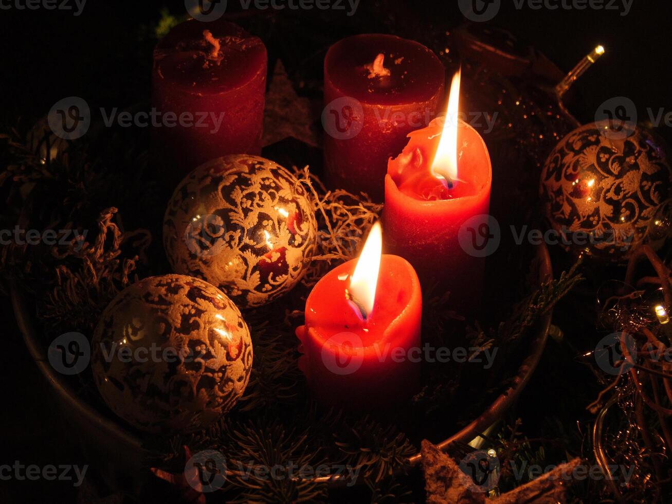 Three red candles are lit in a wreath photo