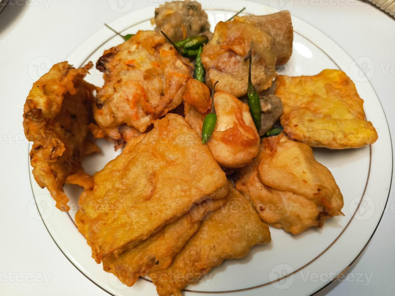photo of a typical Indonesian snack plate consisting of fried tofu, fried tempeh, bakwan and fried banana placed on a white plate