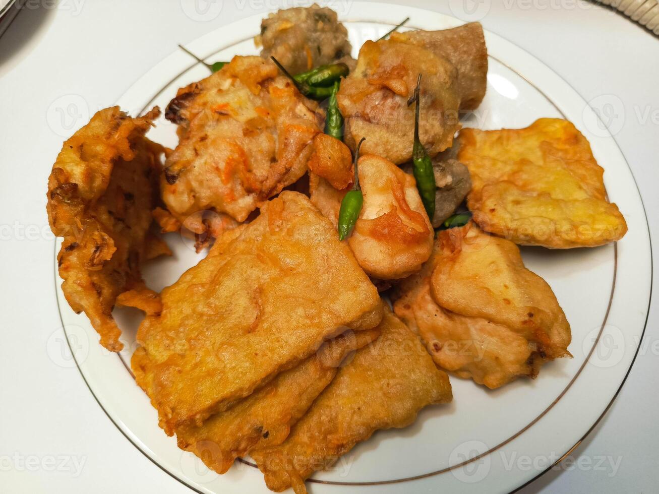 photo of a typical Indonesian snack plate consisting of fried tofu, fried tempeh, bakwan and fried banana placed on a white plate