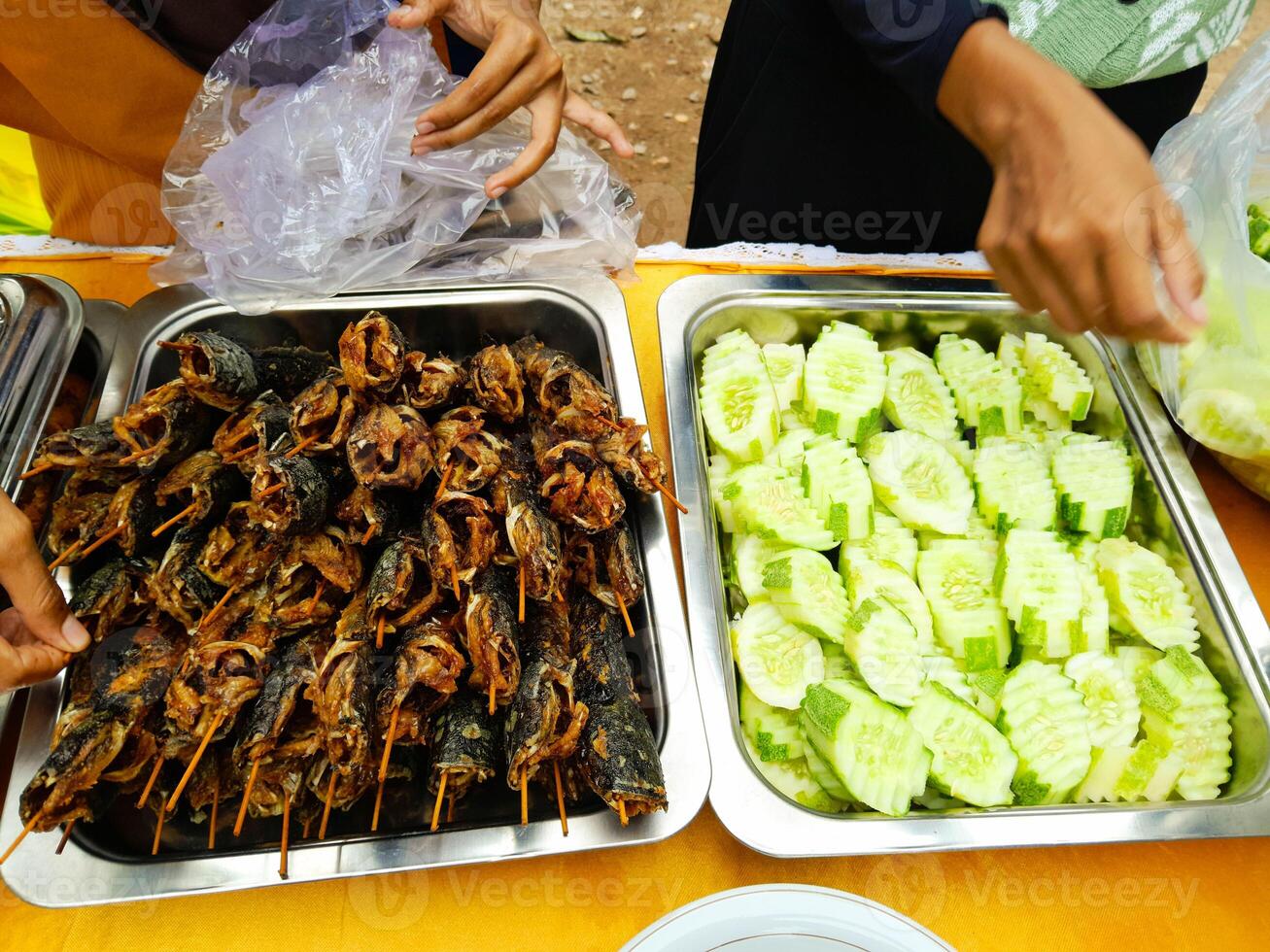 photo of fried catfish and cucumber slices on an aluminum container ready to eat