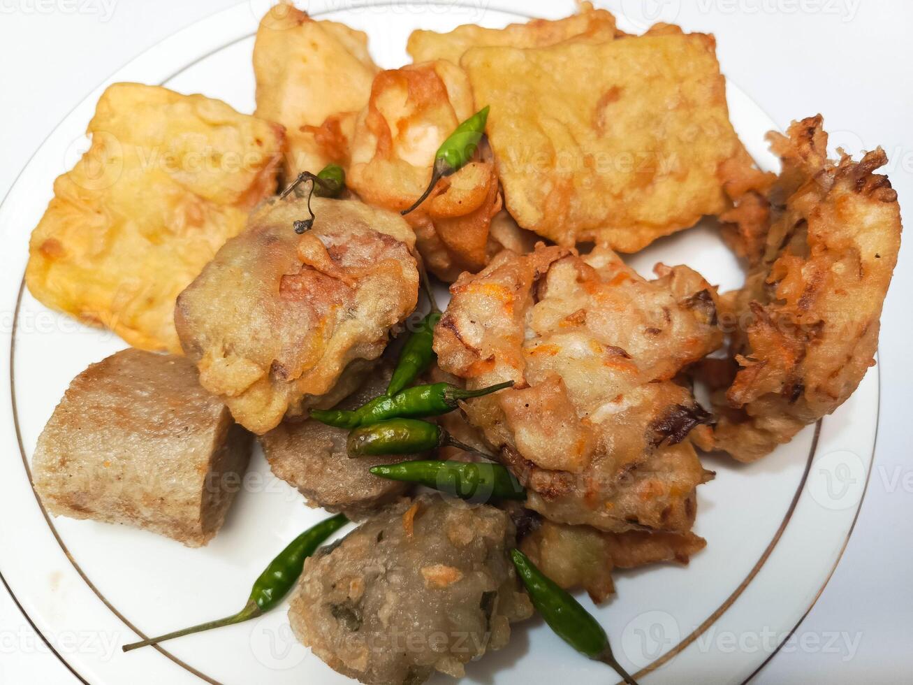 photo of a typical Indonesian snack plate consisting of fried tofu, fried tempeh, bakwan and fried banana placed on a white plate