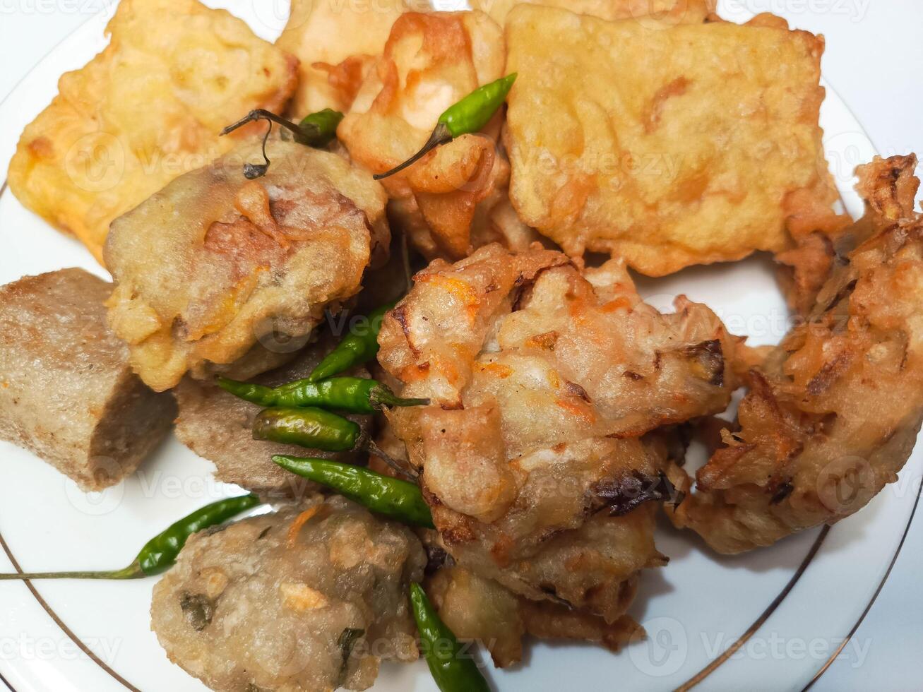 photo of a typical Indonesian snack plate consisting of fried tofu, fried tempeh, bakwan and fried banana placed on a white plate