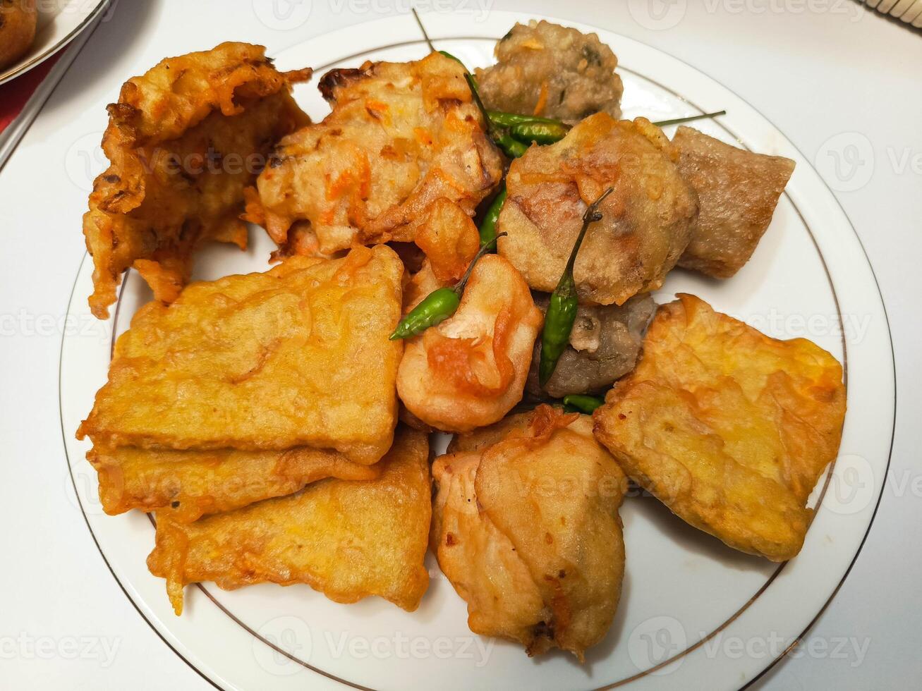 photo of a typical Indonesian snack plate consisting of fried tofu, fried tempeh, bakwan and fried banana placed on a white plate