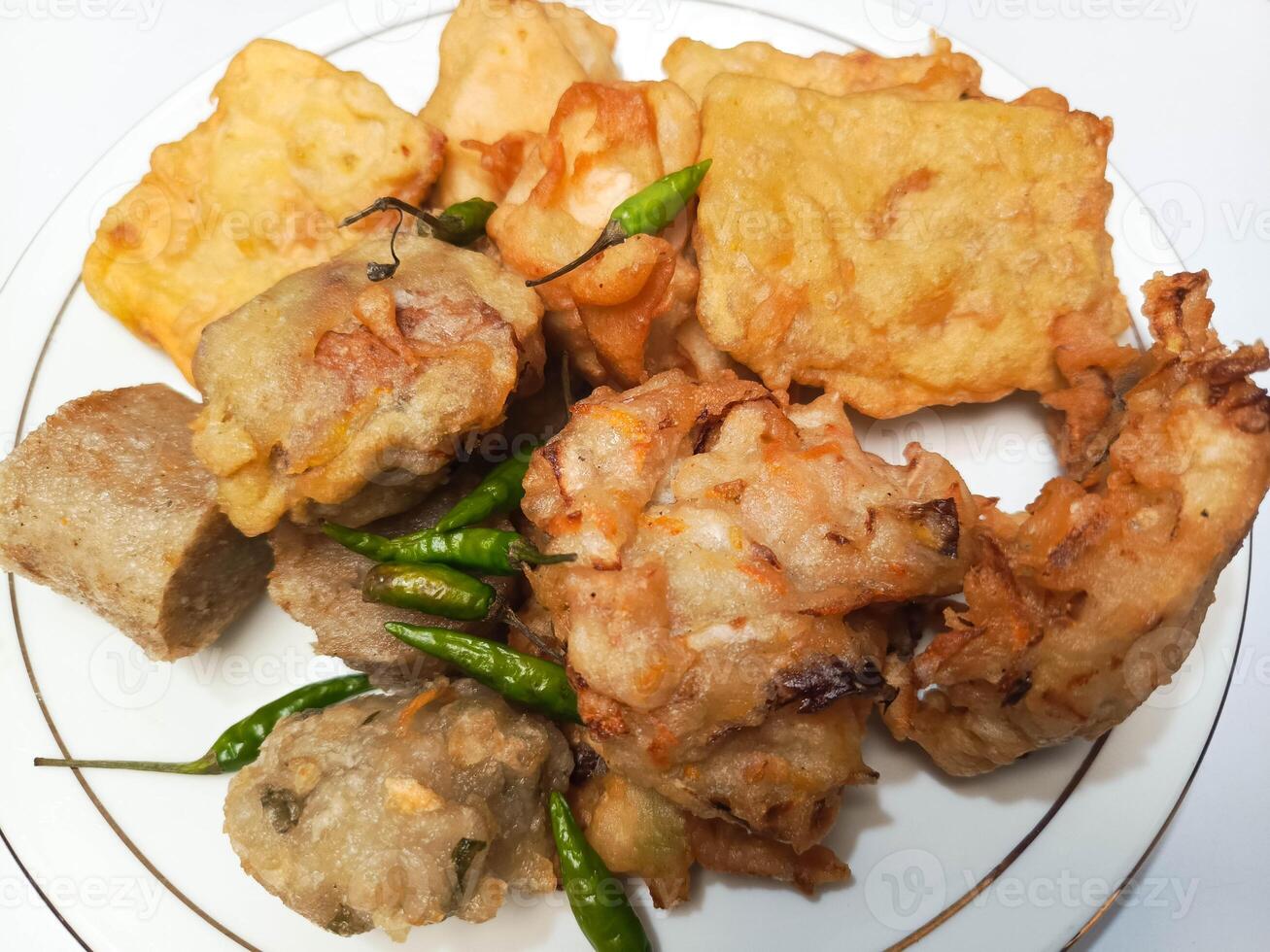 photo of a typical Indonesian snack plate consisting of fried tofu, fried tempeh, bakwan and fried banana placed on a white plate