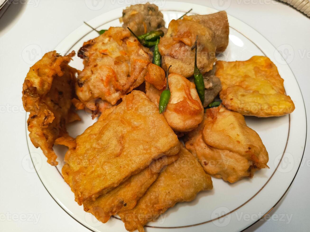 photo of a typical Indonesian snack plate consisting of fried tofu, fried tempeh, bakwan and fried banana placed on a white plate