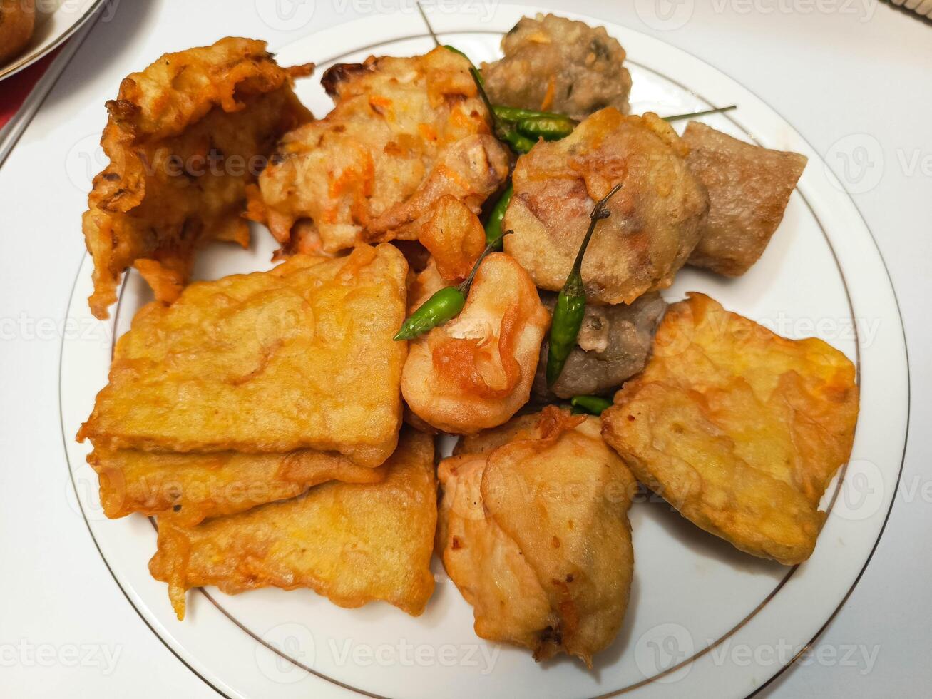 photo of a typical Indonesian snack plate consisting of fried tofu, fried tempeh, bakwan and fried banana placed on a white plate