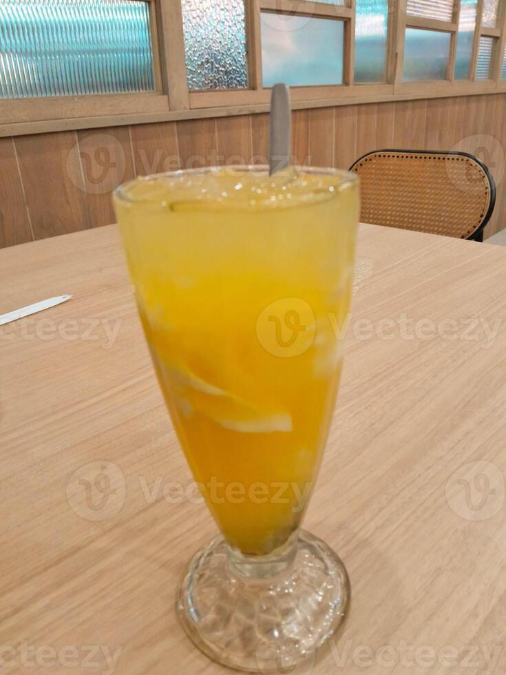 photo of a fresh orange iced drink mixed with shavings of young coconut meat