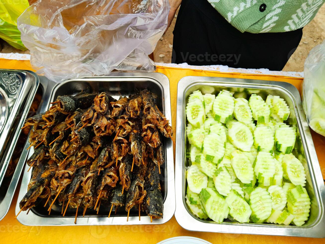 photo of fried catfish and cucumber slices on an aluminum container ready to eat