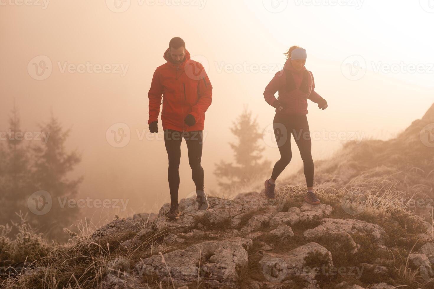 trail running couple man and woman running on a mountain path photo