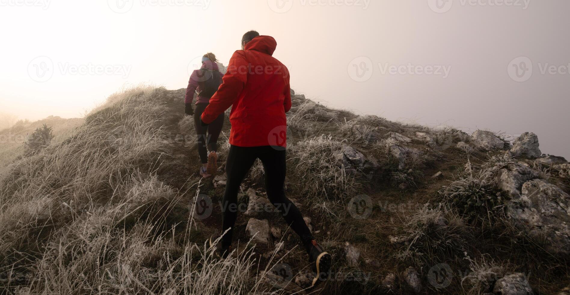 trail running couple man and woman running on a mountain path photo