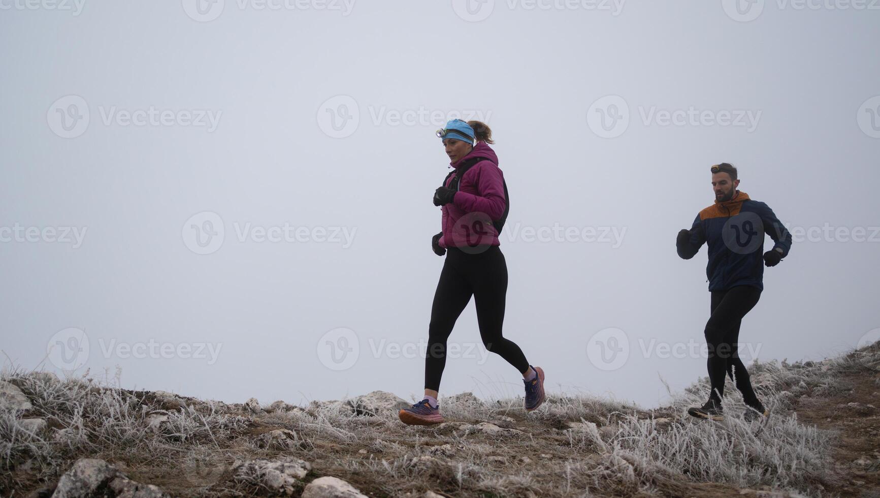 trail running couple man and woman running on a mountain path photo