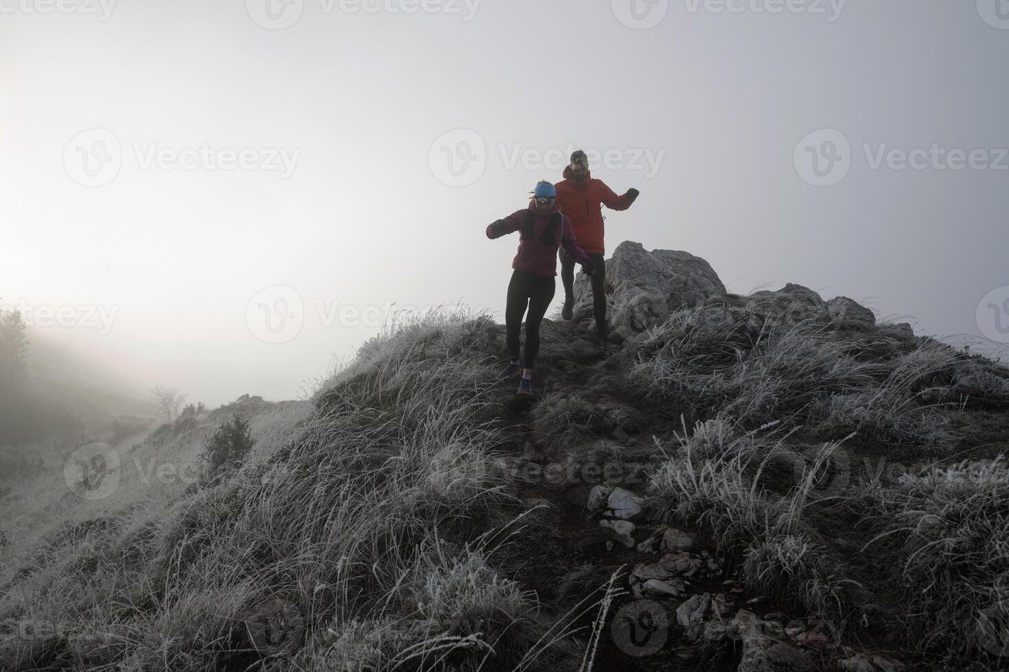 trail running couple man and woman running on a mountain path photo