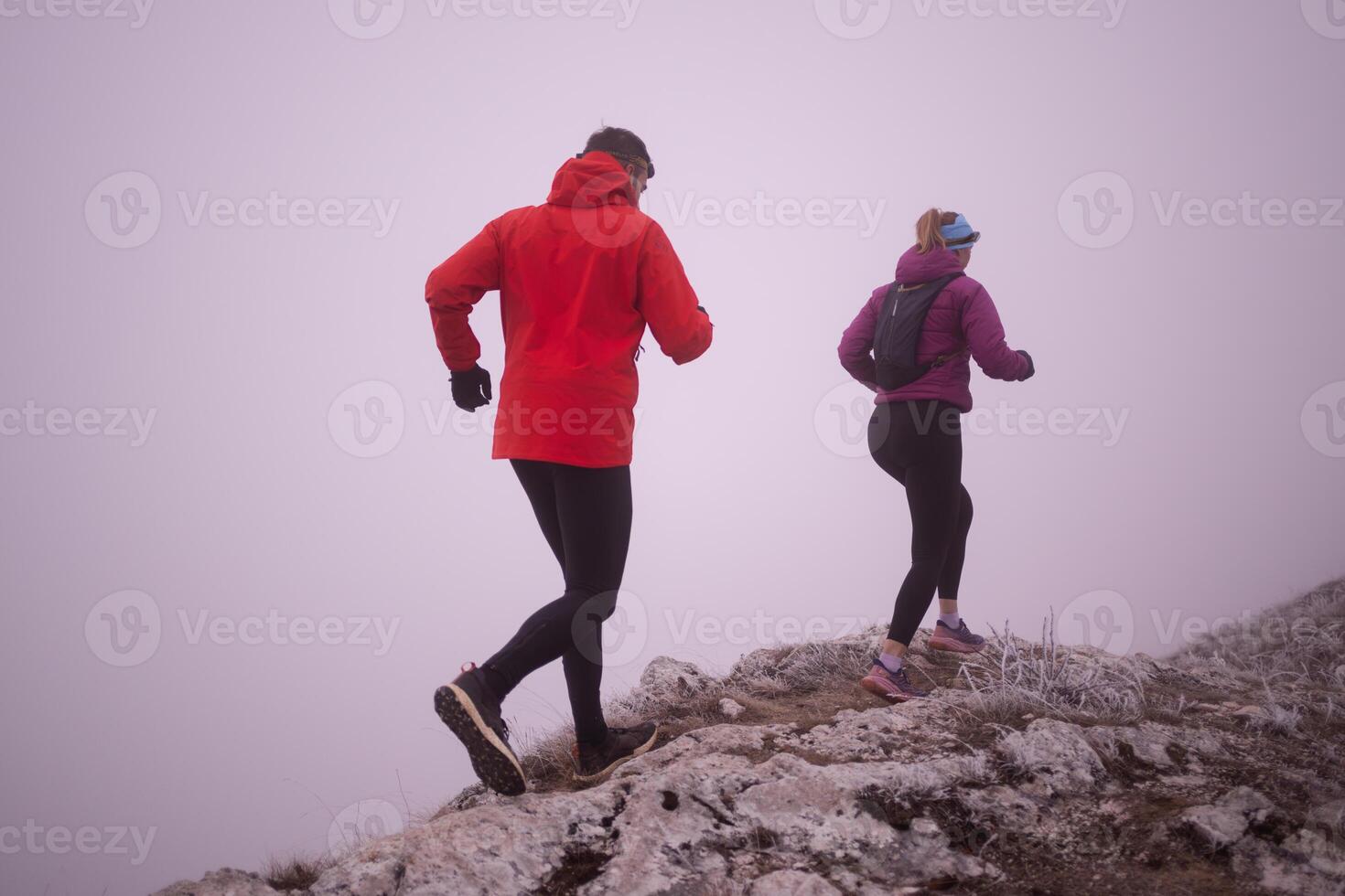 Athlete couple trail running on the mountain top in the early morning. Sky running concept photo