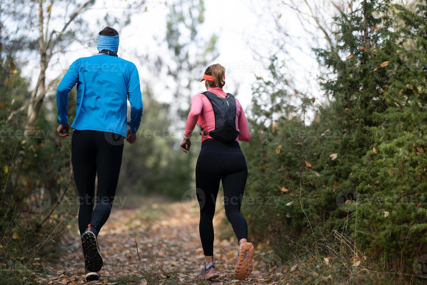 trail running with a sporty couple in the magic forest in early morning photo