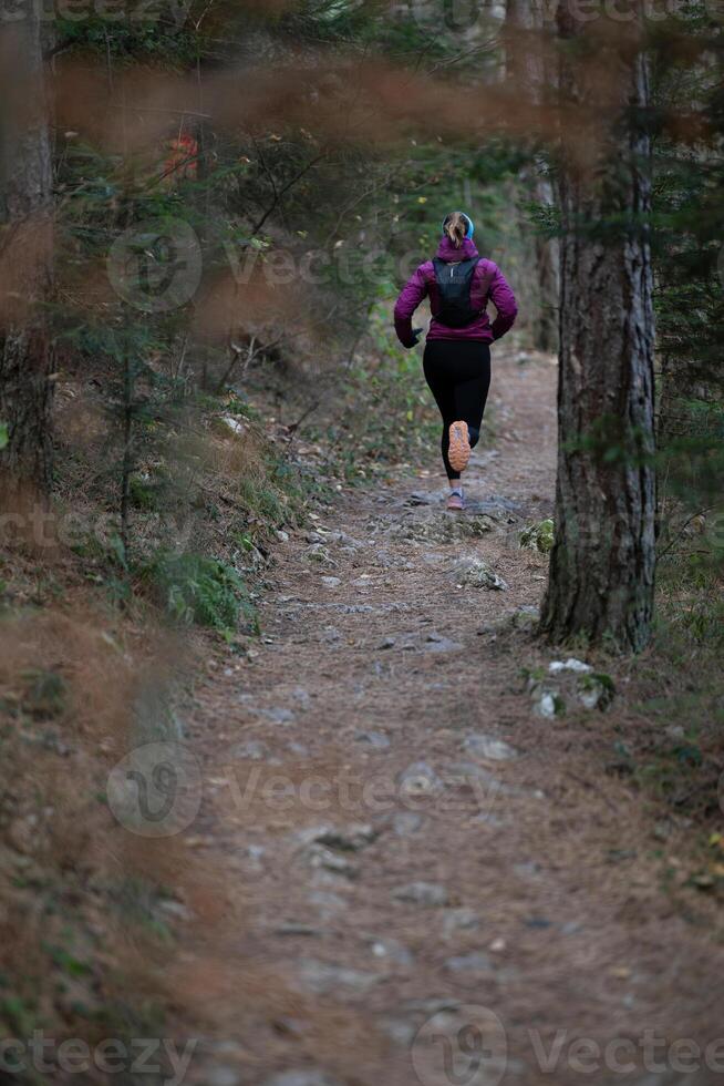 trail running woman athlete training for ultra-marathon race in a mountain photo