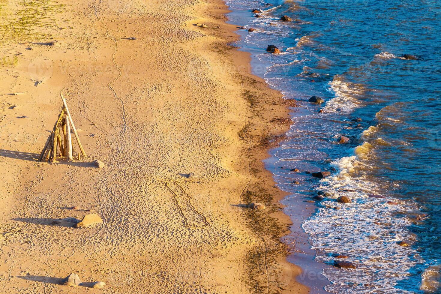 aerial view of a beach with wooden walkways leading through the sand, waves lapping at the shore photo
