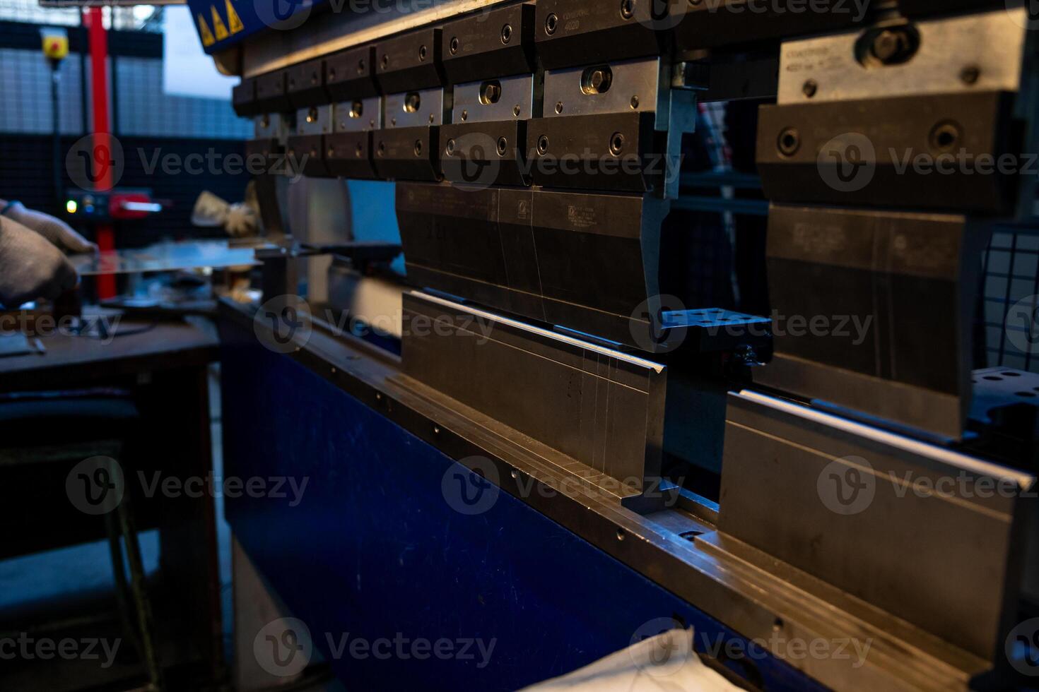 Worker prepares a metal sheet on an industrial press machine, focusing on precision in a factory environment. photo