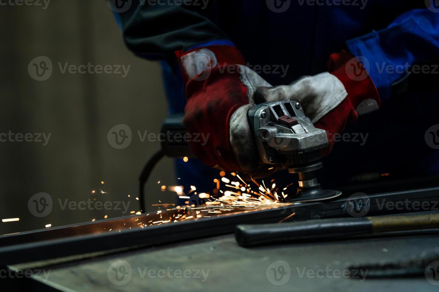 Craftsman using an angle grinder, creating bright sparks while working on a metal frame in the workshop. photo