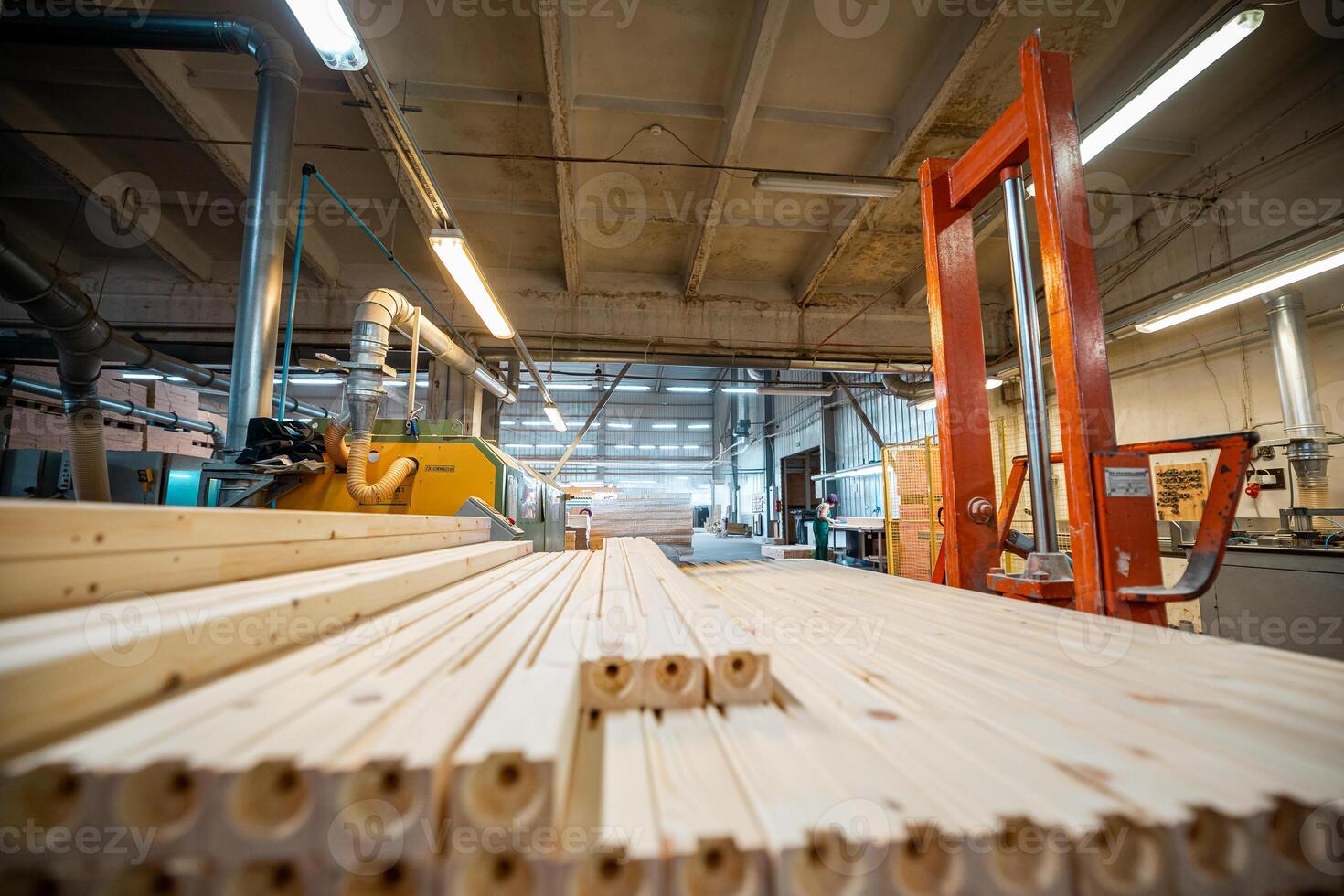 Industrial woodworking facility with stacks of wooden planks and pallets organized for processing, under bright industrial lighting, showcasing a busy and organized work environment photo