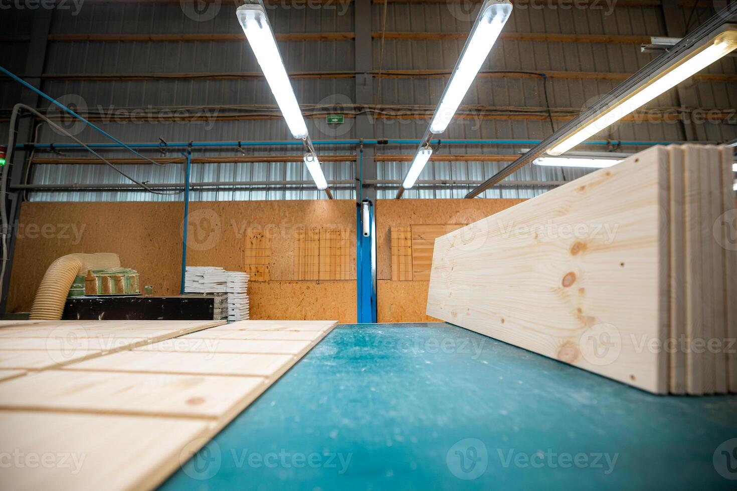 A workbench in a woodworking factory, with wooden beams and tools ready for processing under bright fluorescent lights photo