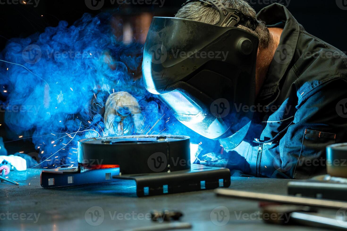 Close up of a welder focused on his work, bright blue light and sparks emanating from the welding torch. photo