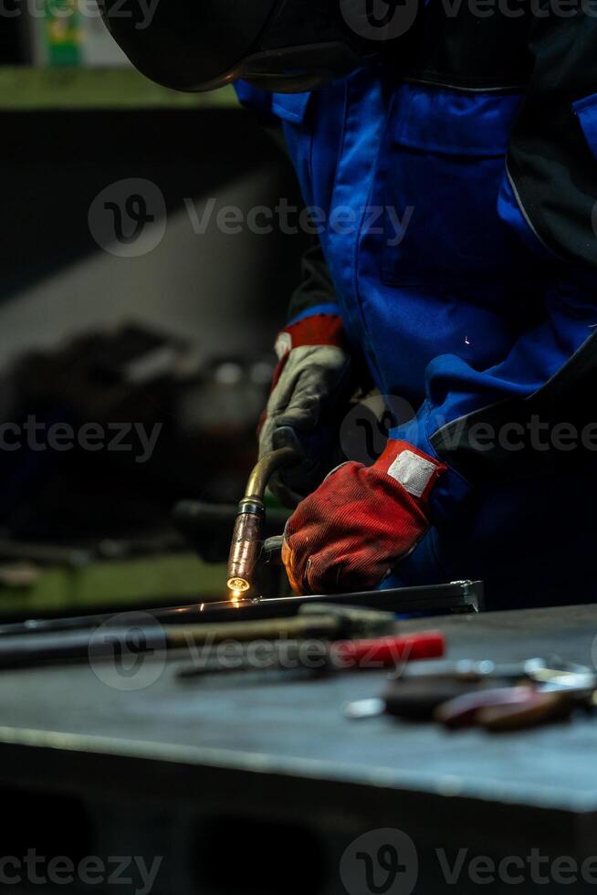 Worker in protective gear handling a welding torch, intense light and sparks flying in the workshop. photo