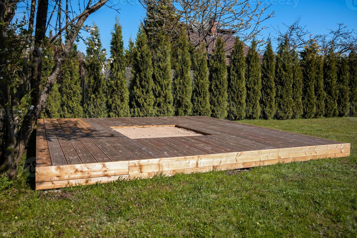 Wooden deck with a central sandpit in a sunny backyard, featuring a clean and simple design photo