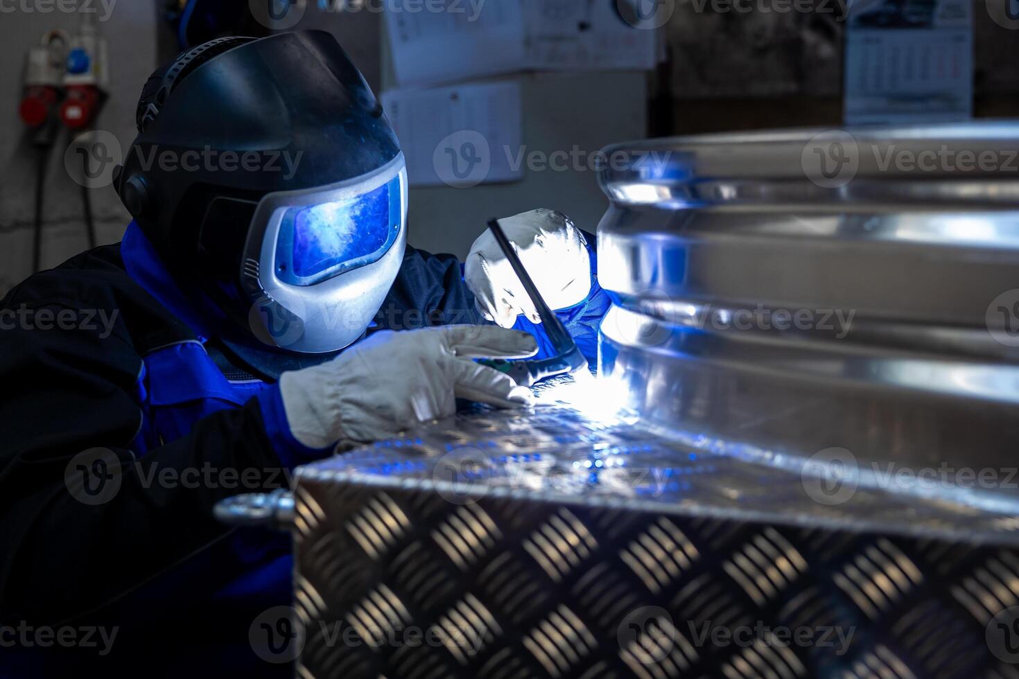 Welder with protective gear welding a metal structure in a workshop, focusing on the bright welding light and precision work. photo