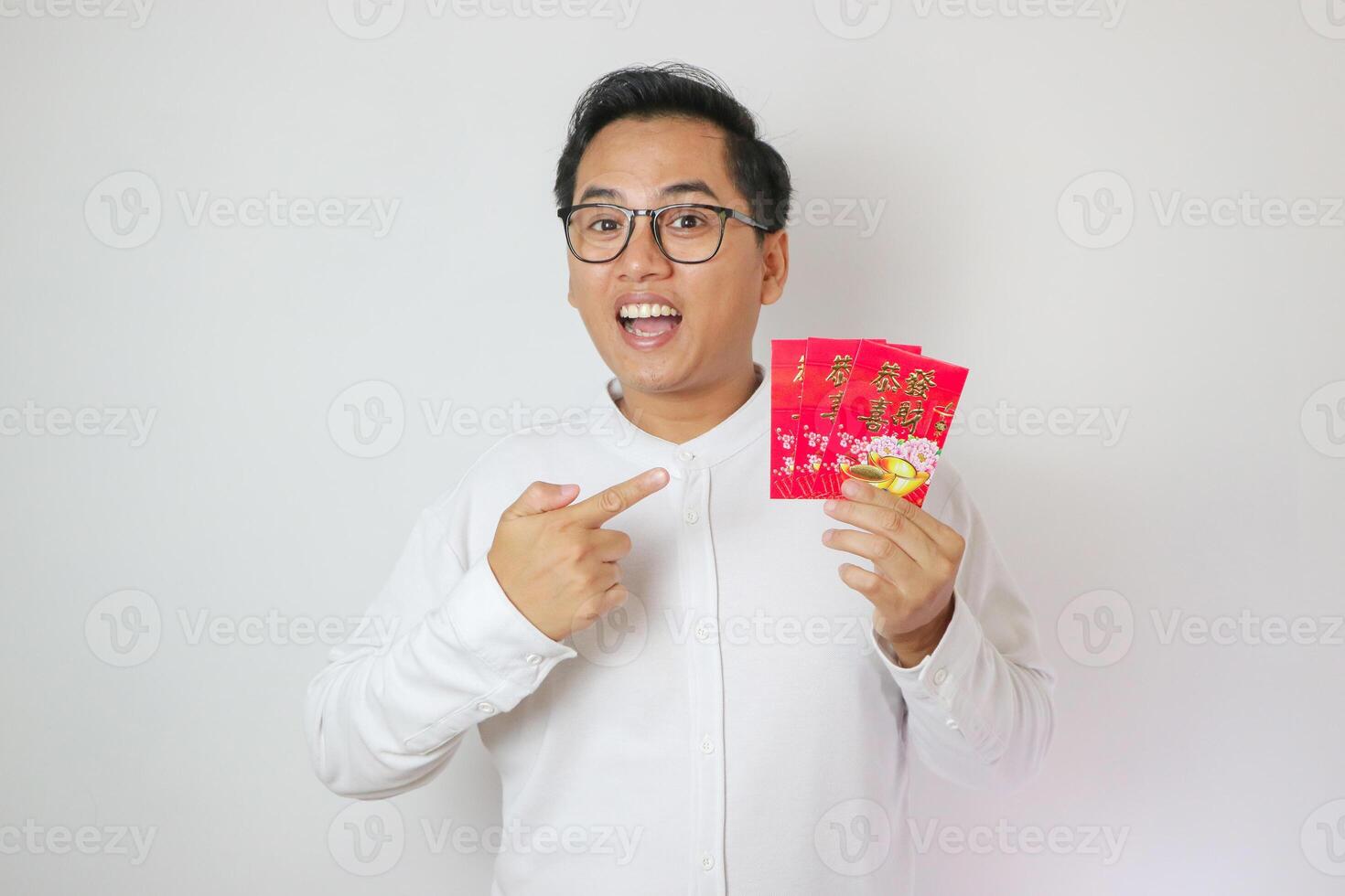 Asian man wearing Cheongsam or Chinese traditional cloth is holding and pointing angpao or red monetary gift on white background. Gong Xi Fa Cai. photo