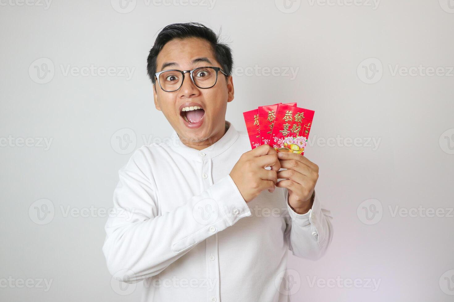 Happy face of Asian man wearing Cheongsam or Chinese traditional cloth while holding angpao on white background. Gong Xi Fa Cai. photo