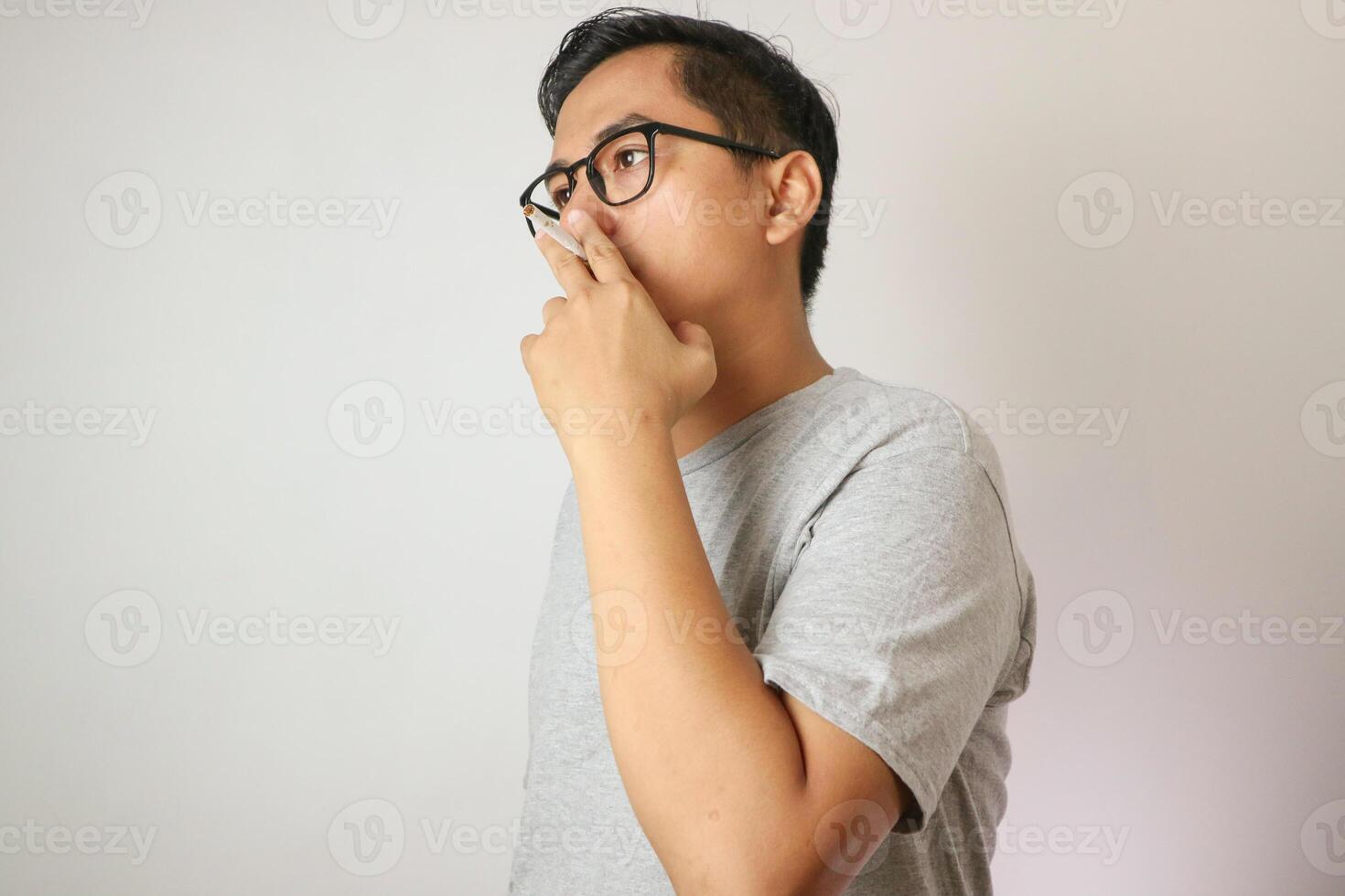 Handsome cool man with Cigarette, going to smoke, isolated on white background, copy space for advertisement. Portrait of asian man in white shirt light cigarette. copy space. Smoking concept. photo