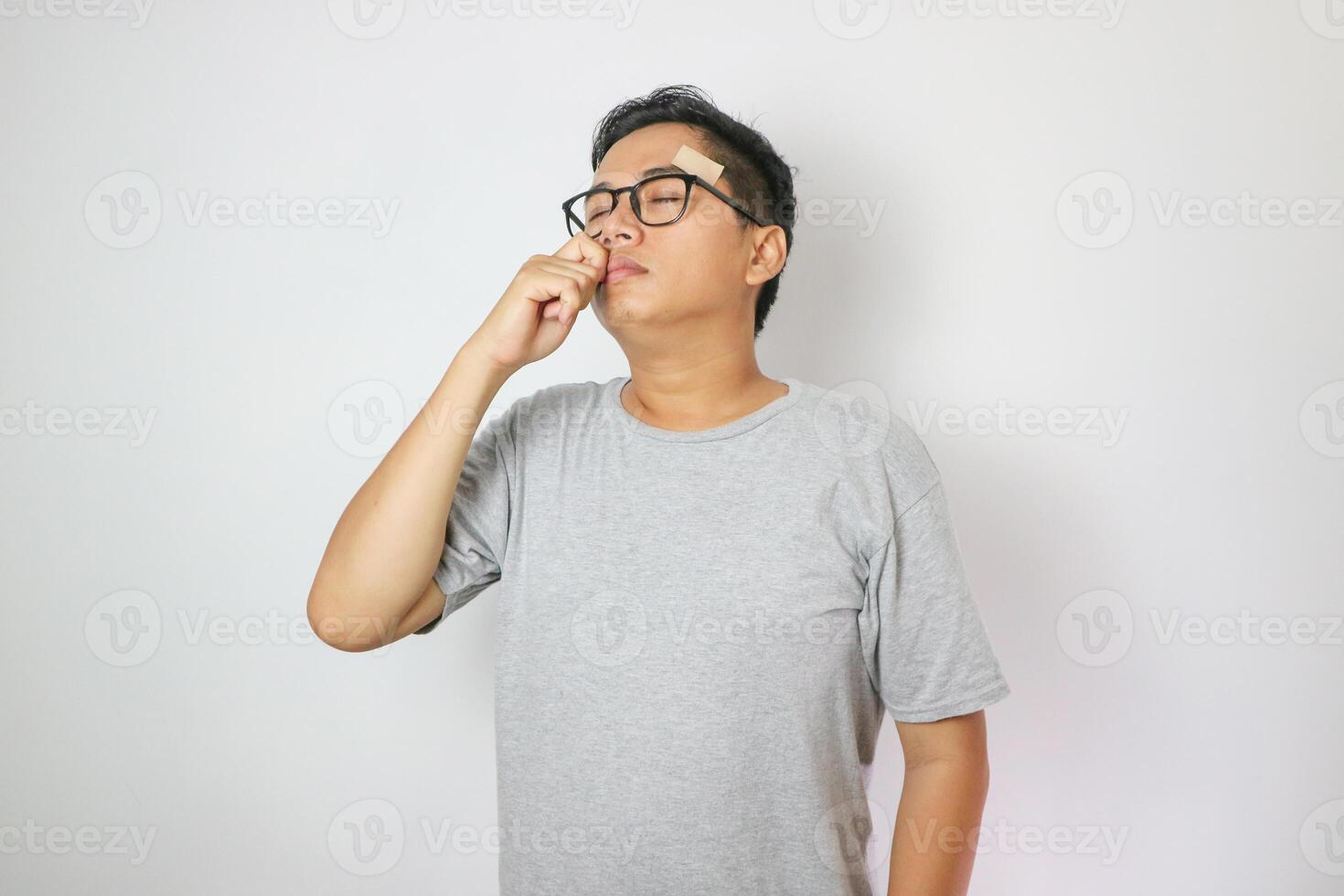 Adult Asian man showing relieved expression when using nasal stick inhaler. photo