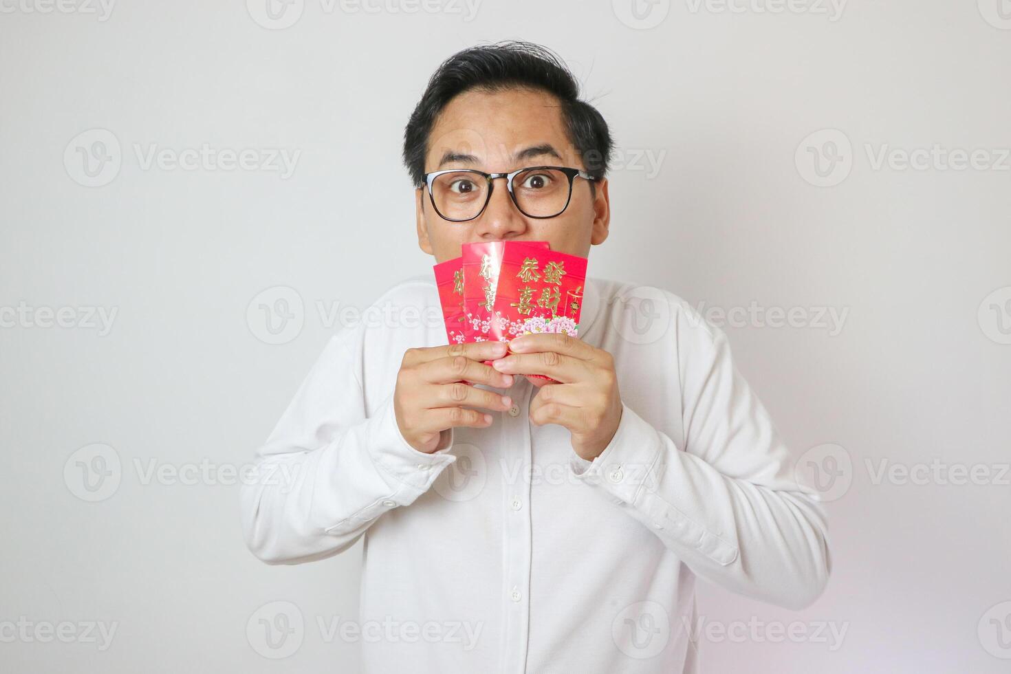 Asian man smelling red envelope white background isolation, chinese new year celebration concept. photo