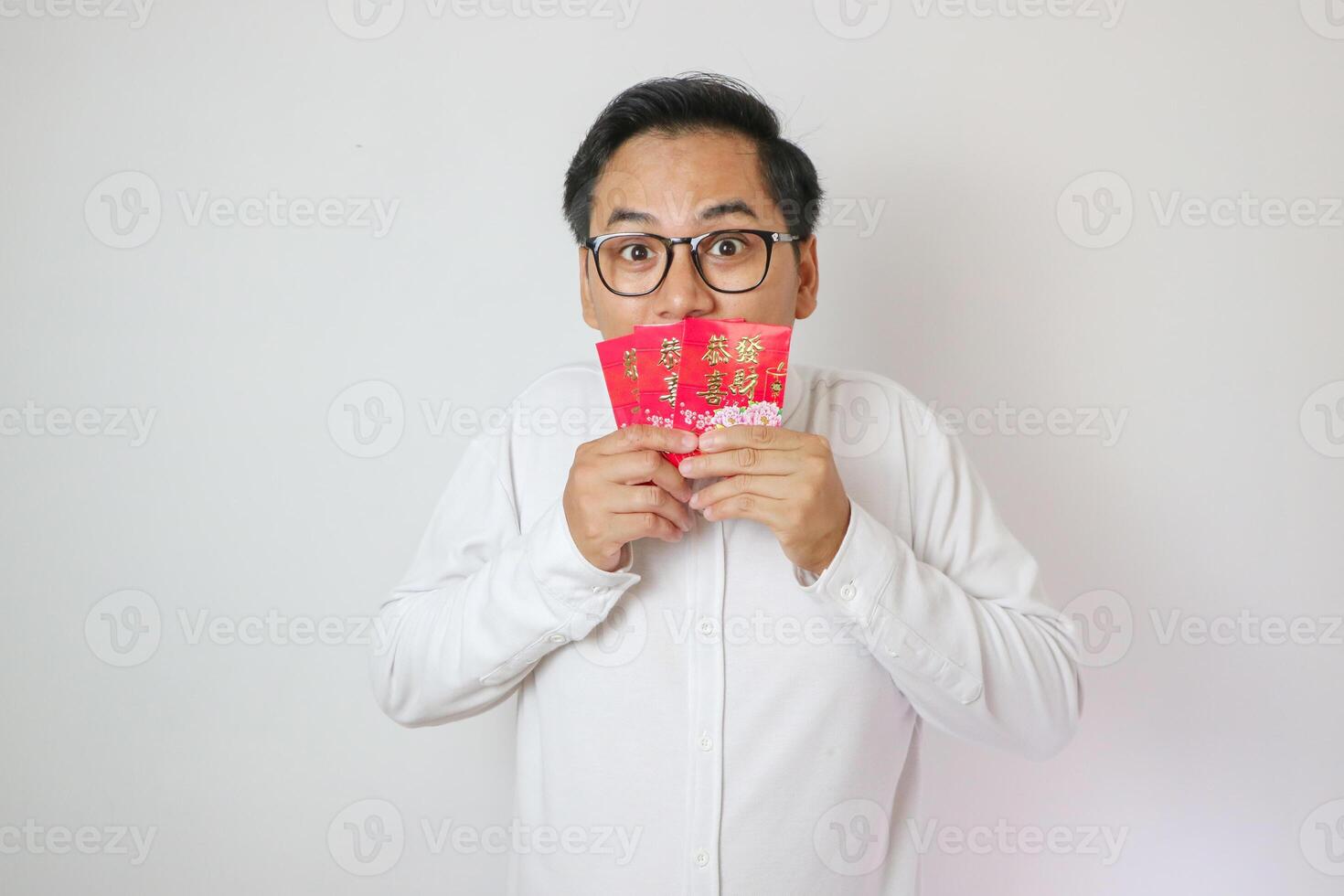 Asian man smelling red envelope white background isolation, chinese new year celebration concept. photo