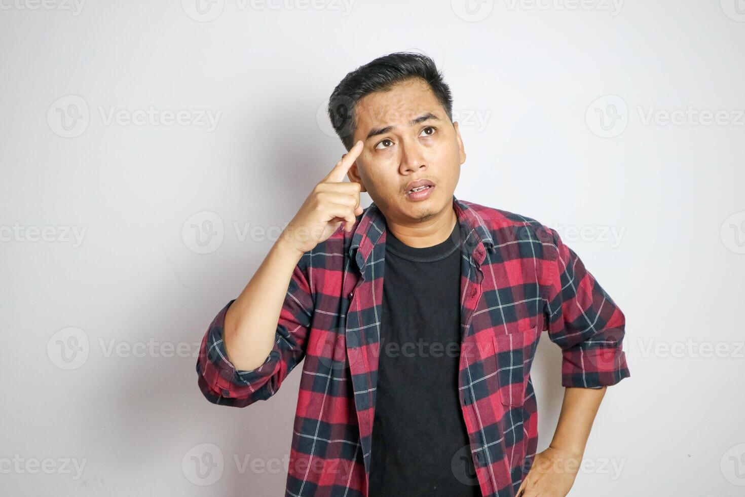 Adult Asian man pointing to his temple with confuse expression photo