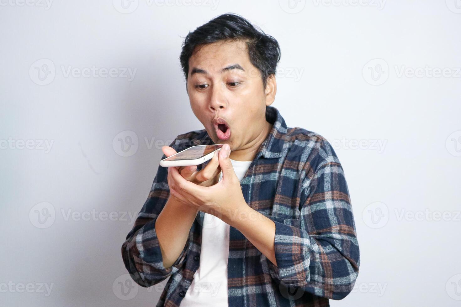 Happy asian funny man standing while on phone with loud speaker mode. Isolated on white background photo