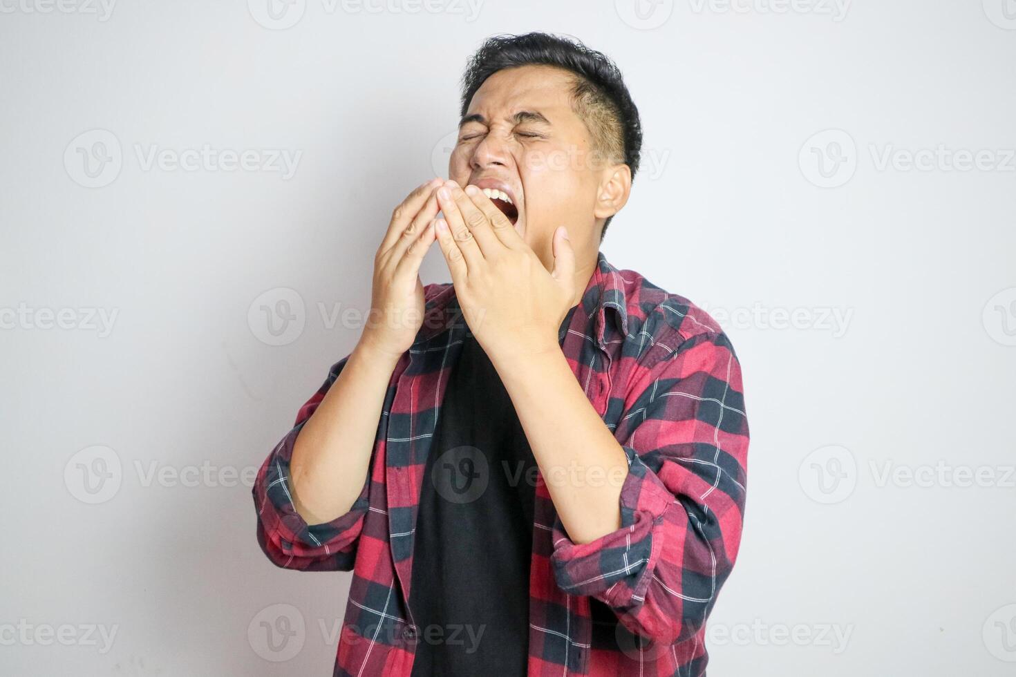 A Southeast Asian man sneezing while holding his nose. Captures a moment of discomfort, suitable for themes related to health, allergies, or cold symptoms in various marketing or editorial contexts photo