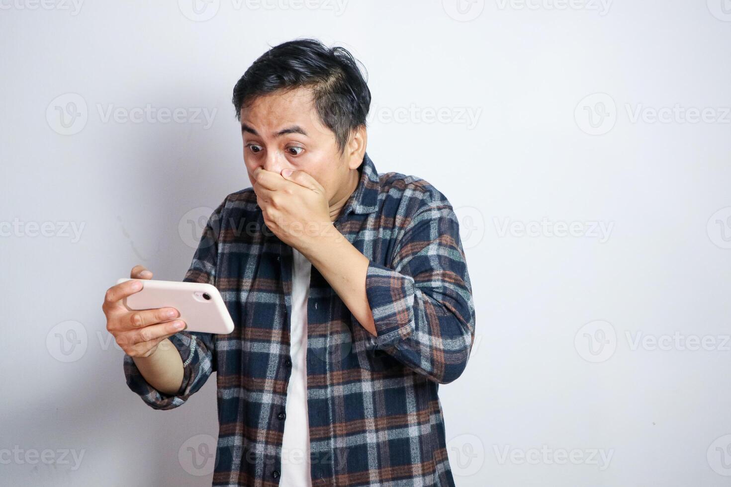 Oh No. Portrait of emotional shocked asian guy holding and using smartphone, seeing surprising news, photos or message. Surprised man grabbing head isolated over white studio background wall