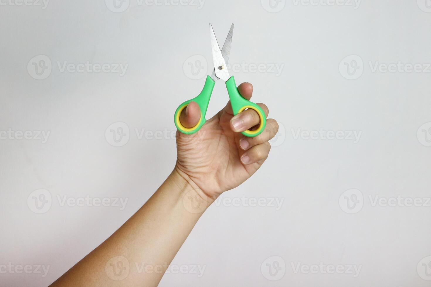 Hand holding a green scissors on white background photo