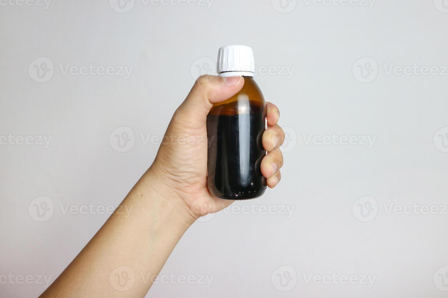 Image of hands with table spoon and bottle of medication. Pouring cough syrup or cold liquid medication into spoon. Bottle with no label. photo