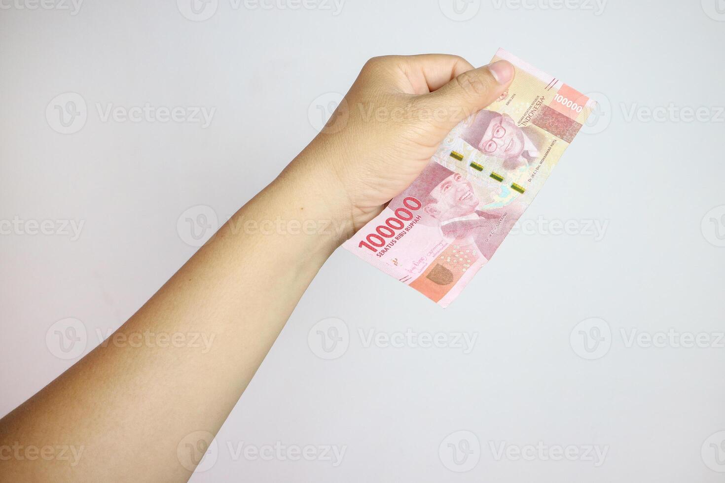 hand holding IDR 100,000 rupiah note isolated on white background. concept of finance and financial photo