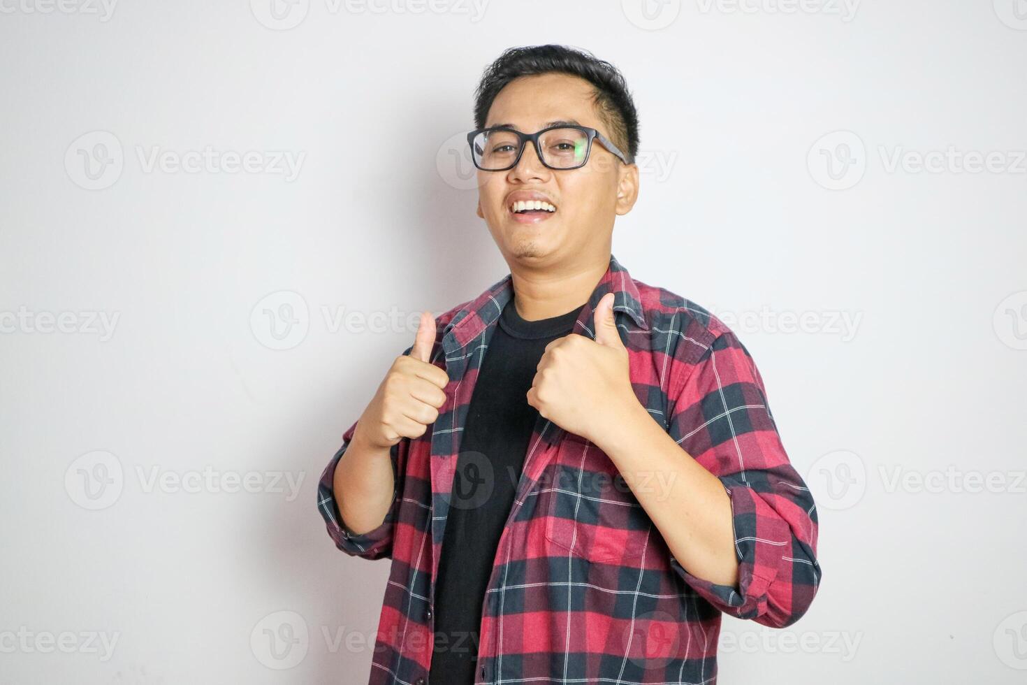 A happy Filipino man giving a rousing thumbs up in approval. In a white shirt and gray windbreaker. Isolated on a white backdrop. photo