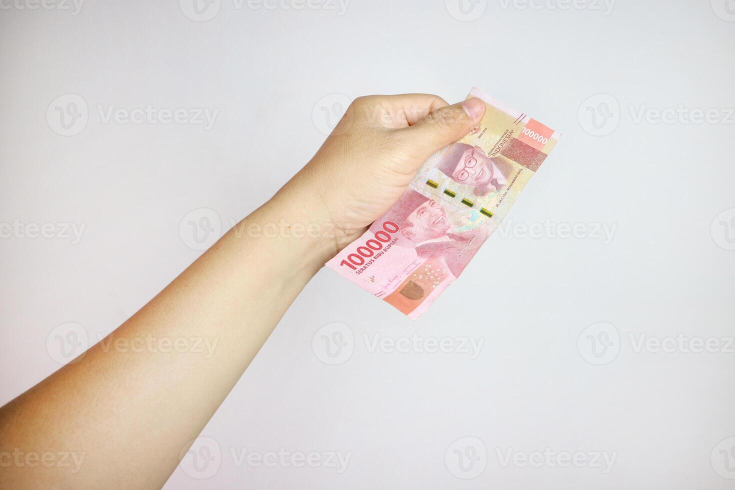 hand holding IDR 100,000 rupiah note isolated on white background. concept of finance and financial photo