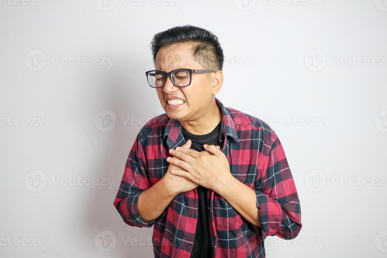asian man holding hands on chest suffering from heart attack, closeup. photo