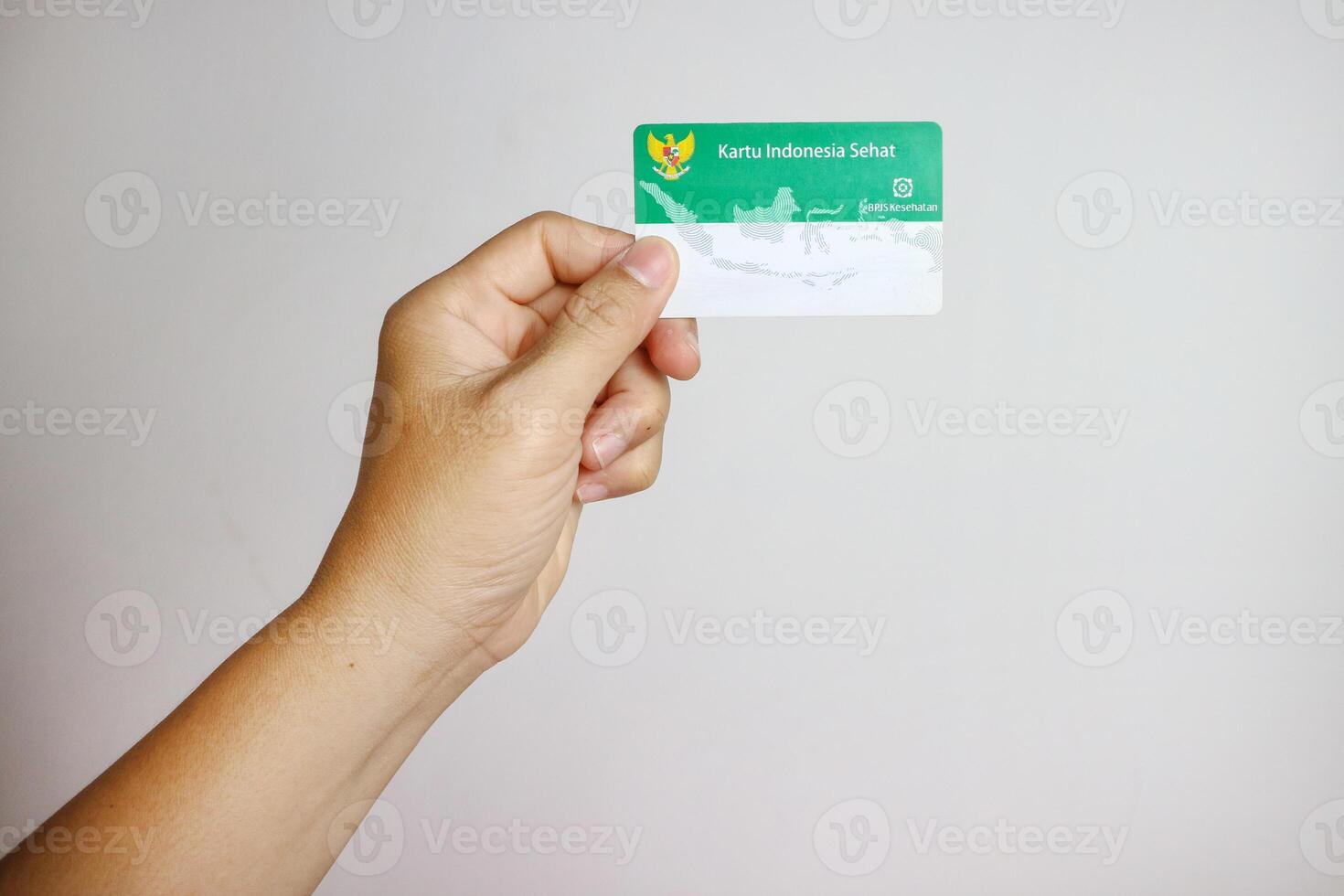Hand holding Indonesian Government Health Insurance Card or Kartu BPJS Kesehatan isolated on white background, Magelang-Indonesia, 16-07-2023 photo