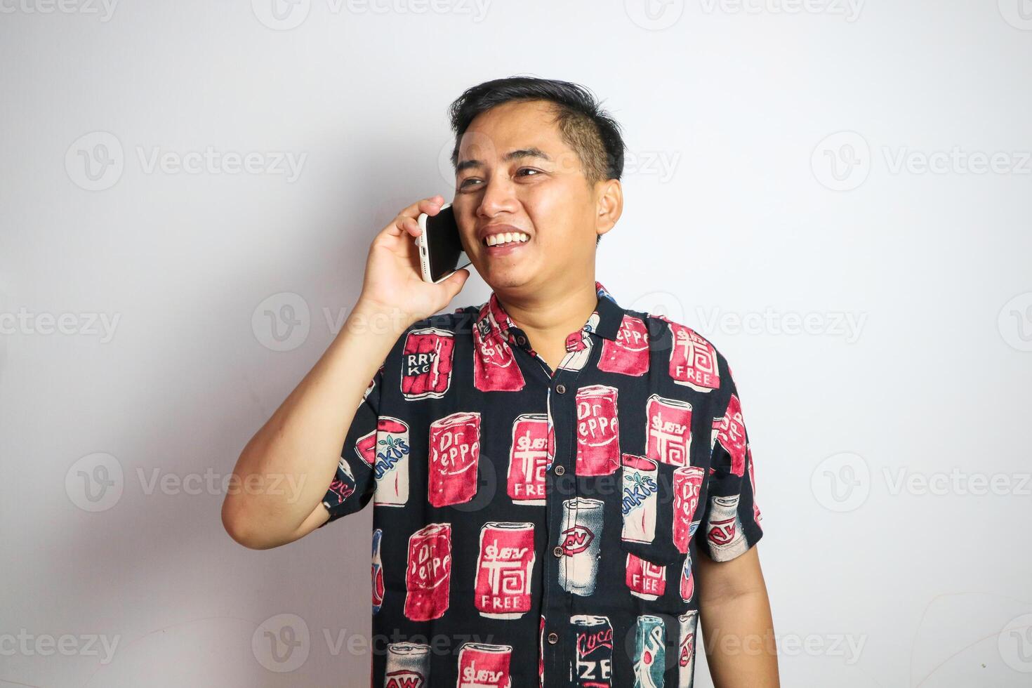 A fun, excited Asian man tourist in summer clothes and sunglasses is talking on the phone with someone, posing with a luggage on an isolated white background. summer vacation, beach trip, journey photo